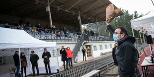 Der Bezirksbürgermeister von Mitte winkt mit blumen ins Publikum eines stadions