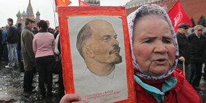 Ältere Frau hält Bild von Lenin in der Hand.