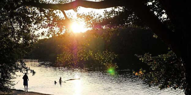 Kinder baden bei Sonnenuntergang im See