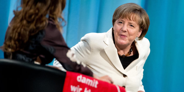 Angela Merkel sitzt beim Kirchentag 2015 auf einer Bühne