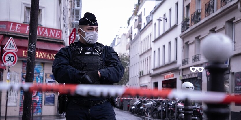 Ein Polizist steht hinter einem Absperrband auf einer Straße