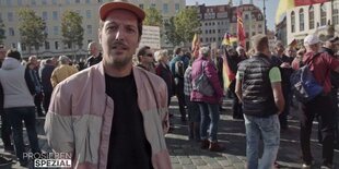 Szene aus Doku, Mann mit Mütze auf einer Demo