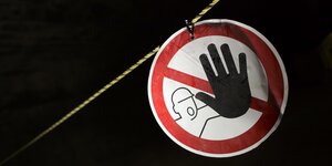 Im Dunkeln hängt ein weißes Schild mit rotem Rand und einer abwehrenden schwarzen Hand: "Betreten verboten"