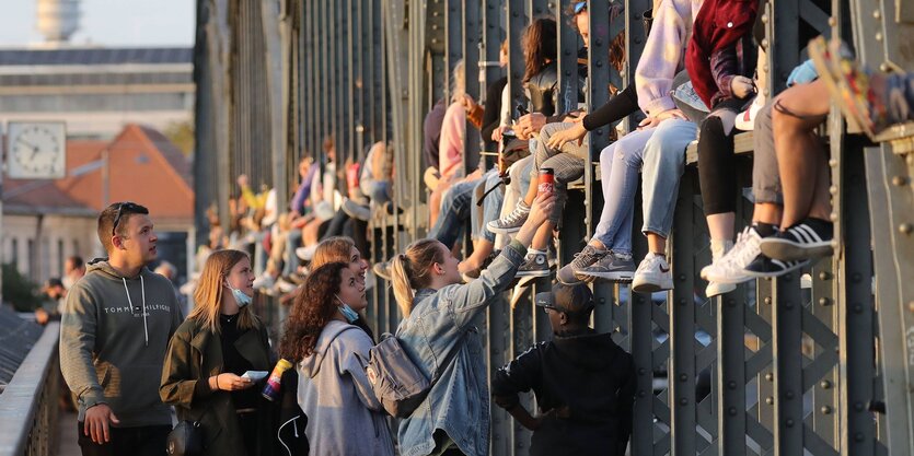 Jugendliche sitzen auf dem Geländer einer Brücke und genießen den Sonnenuntergang