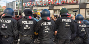 Polizisten stehen bei einer Black-Lives-Matter-Demo in voller Kampfmontur vor dem S-Bahnhof Alexanderplatz. Sie tragen Helm und haben Nummern auf dem Rücken.