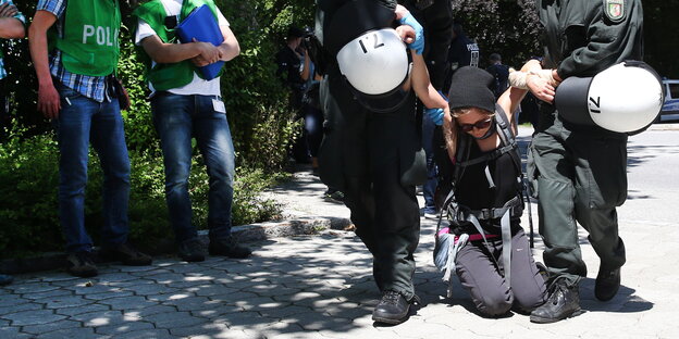 Polizisten tragen eine Demonstrantin weg Polizisten tragen eine Demonstrantin weg