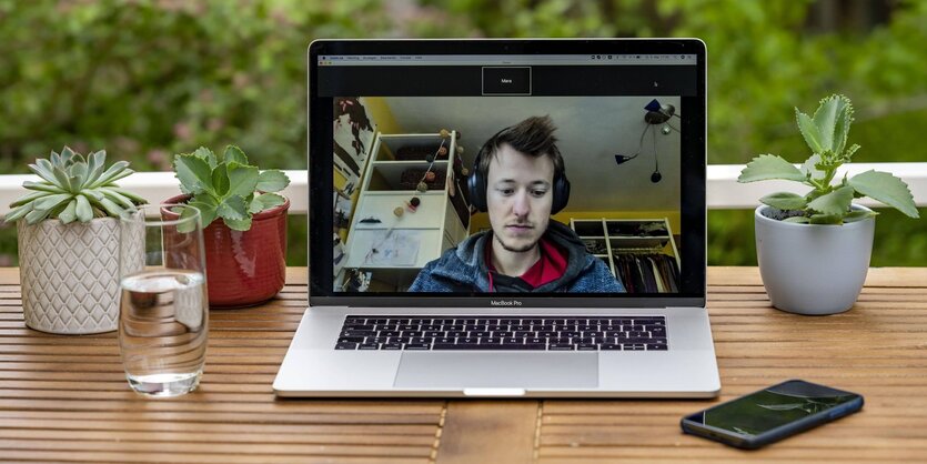 Ein Laptop mit geöffnetem Videochatprogramm steht auf einem Balkon