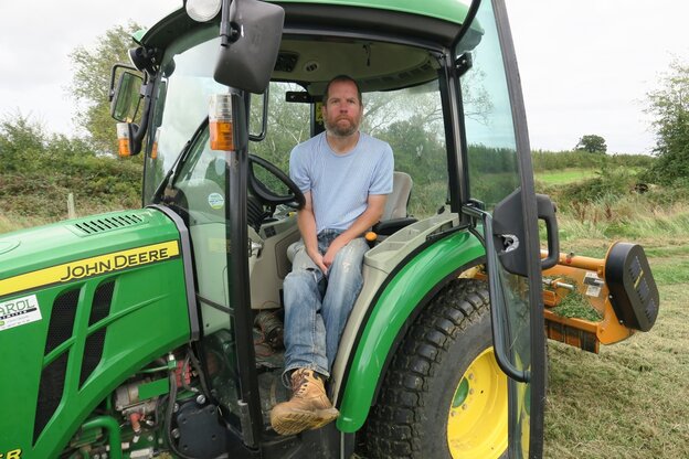 Ein Mann mittleren Alters sitzt im Fahrerhaus eines Traktors Ein Mann mittleren Alters sitzt im Fahrerhaus eines Traktors