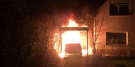 Ein AUto brennt mitten in der Nacht in einem Carport direkt neben einem Wohnhaus