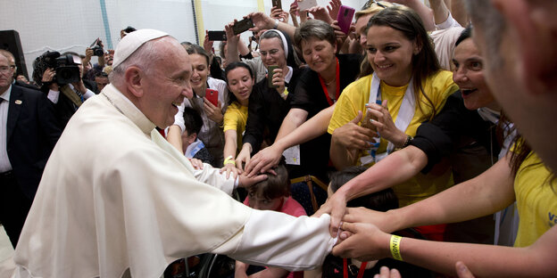 Der Papst schüttelt Gläubigen die Hände.