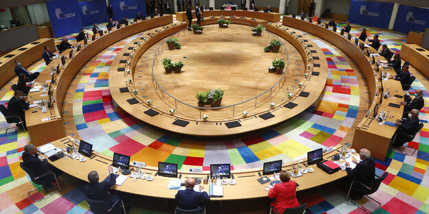 Blick von oben auf einen Sitzungsraum in Brüssel, in dem Staats- und Regierungschef an einem großen Rund aus Tischen sitzen