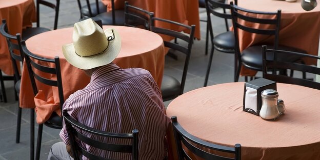 Ein Mann mit einem Cowboyhut sitzt an einem Restauranttisch