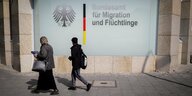 Zwei Menschen gehen am Bundesamt für Migration und Fluechtlinge in Berlin vorbei