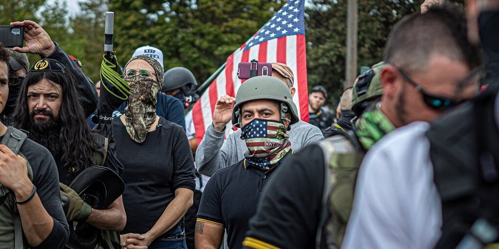 Männer und ein Frau die zu der Gruppierung der Proud Boys gehören, einer trägt einem M;undschutz in den Farben der amerikanischen Flagge