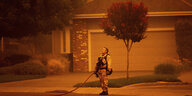 Ein Feuerwehrmann in Kaifornien steht auf der Straße, er hat seinen Helm abgesetzt und schaut verzweifelt