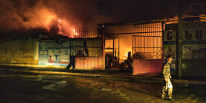 Ein Soldat geht in der Nacht an einem brennenden Gebäude vorbei.
