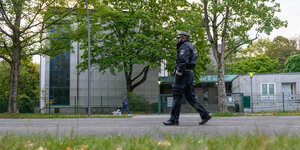 Ein Polizist patroulliert auf der Straße vor dem Eingangsbereich der Hamburger Synagoge