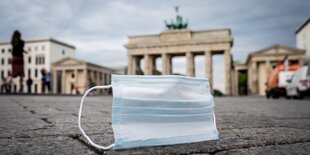 Ein Mund-Nasen-Schutz wird vom Wind über den Pariser Platz vor dem Brandenburger Tor in Berlin geweht.