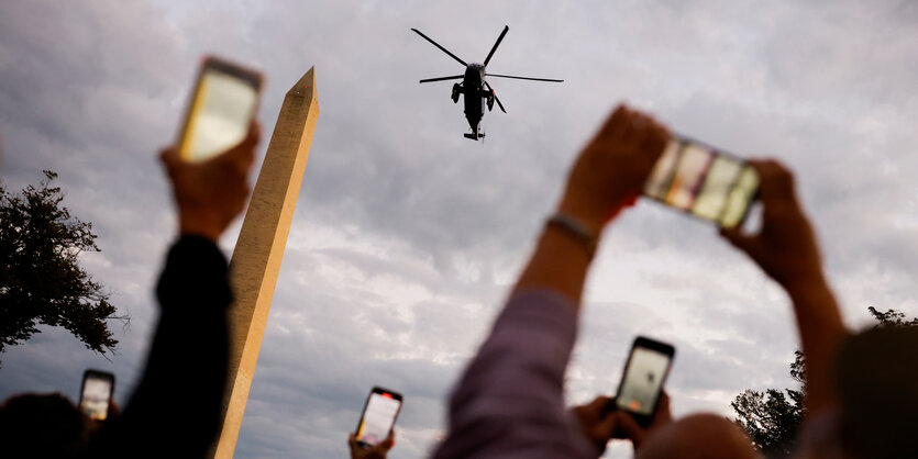 hochgereckte Handys fotografieren Trumps Hubschrauber