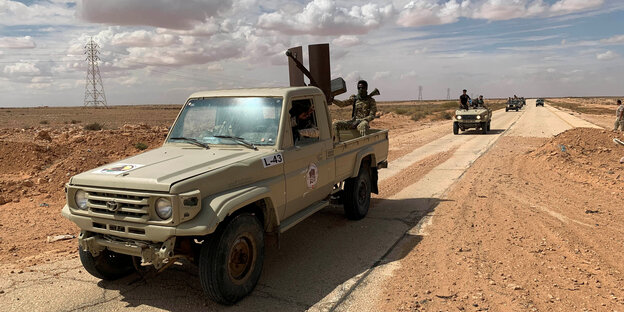 Kämpfer auf Pick-Ups fahren durch die Wüste