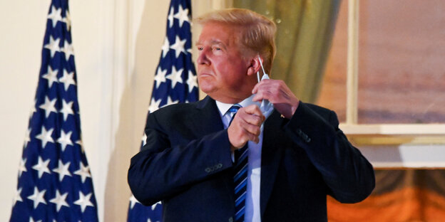 Donald Trump nimmt seinen Mundschutz ab.