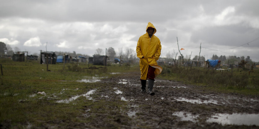 Mann in Regenkleidung vor einem Zeltlager