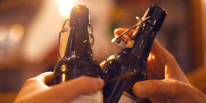 Zwei Leute stoßen mit Bierflaschen an – ab 10.10.20 gilt eine Speerstunde in Berlin (ab 23 Uhr bis 6 Uhr)