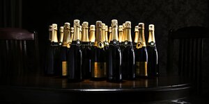 Eine Reihe von Champagnerflaschen vor dunklem Hintergrund
