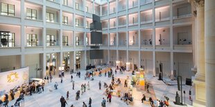 Blick in die große lichtdurchflutete Halle des Humboldt Forum im Berliner Schloss, in der eine Menge Menschen herum wimmeln