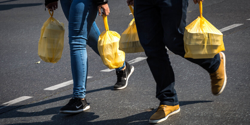 Zwei Menschen laufen mit verpackten Menues über die Strasse.