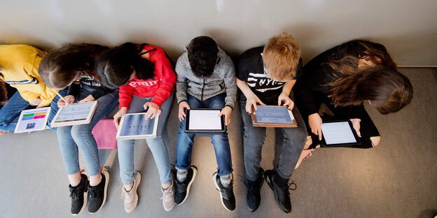 Sechs Schüler aus der Vogelperspektive fotografiert sitzen an ihren iPads
