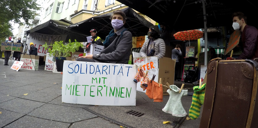 Bewohner:innen der Wiener Straße 20 sitzen in selbstbemalten Umzugskartons auf der Straße.Vol