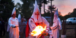 Drei Menschen in Ku-Klux-Klan-Kostümen