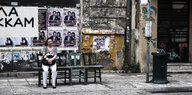 Eine Frau sitzt in Athen an einer improvisierten Bushaltestelle