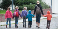 Eine Frau geht mit fünf Kindern über die Straße