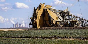 Schaufelradbagger im RWE Braunkohletagebau Garzweiler baggert an der Abrisskante bei Keyenberg, hinten ein Windpark und das Braunkohlekraftwerk RWE Kraftwerk Neurath