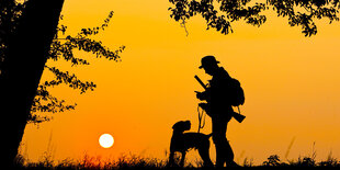 Jäger mit Hund im Sonnenuntergang