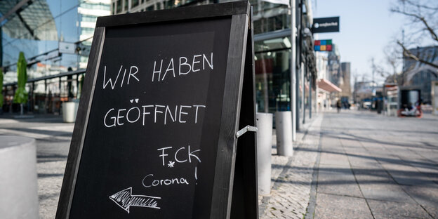 Schild mit Fuck Corona vor einem Cafe