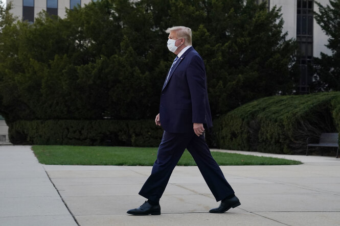 Donald Trump in dunklem Anzug und mit weißer Maske