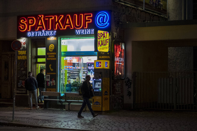 Menschen stehen nachts vor einem Spätverkauf in Berlin