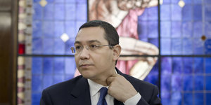 Der rumänische Ministerpräsident Victor Ponta greift an seinen Hemdkragen