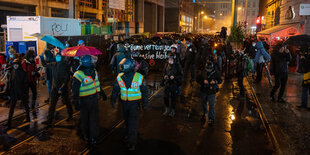 Demonstranten ziehen durch eine Straße bei Regen.