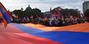 Hunderte von Demonstranten. Viele von ihnen tragen gemeinsam eine riesige Fahne von Armenien und spannen sie so über den Platz in Berlin.