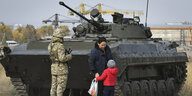 Mutter mit Kind vor Panzer auf der Straße