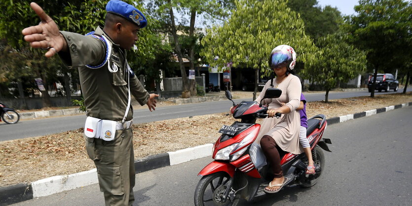 Eine Frau auf einem Roller und ein Polizist