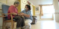 Eine besorgte Heimbewohnerin in einem Pflegeheim wird von ihrer Pflegerin beruhigt