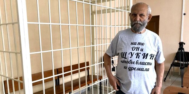Ein Mann mit bedrucktem T-Shirt vor einem Gitterkäfig