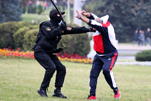 Ein Polizist prügelt auf einen Demonstranten mit erhobenen Händen.