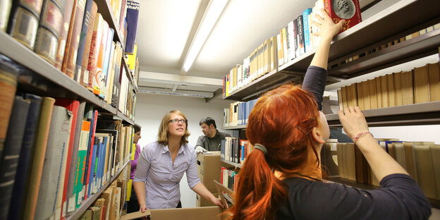 Mitarbeiter der Uni Rostock räumen Bücher in Regale