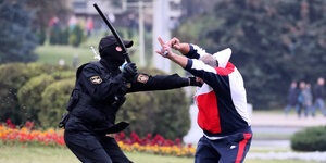 Ein Polizist knüppelt auf einen Demonstranten.